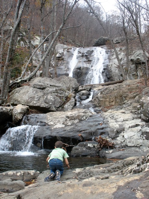 Child playing at base of waterfall.